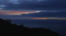Redwood Trees Silhouetted On Steep Mountain With The Pacific Ocean In The Backdrop; As The Sunsets Through To Darkness.
