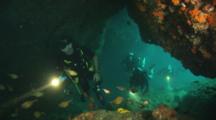 Scuba Divers With Flashlights Explore Underwater Cave