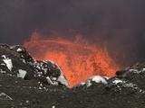 Splattering Lava Seen Over Rocky Lip Of Crater, Slow Zoom In To Waves Of Lava Crashing, Zoom Out To Crater Lip