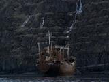 Snow-Topped Rocky Cliff, Rusting Fishing Boat Beneath