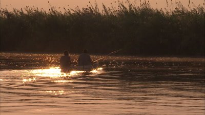 Two Fisherman in mokoro at sunrise on river