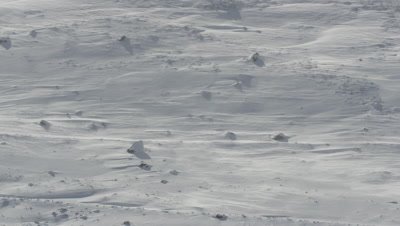 Snow blowing in the wind across the rocky terrain 