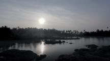 Motion Control Shot Of The Silvery Reflection Of The Sun Rising. Dawn Over The Small Harbour Of Arambol In , Goa, India. The Smoke In The Palms Comes From The Breakfast Fires Outside The Huts.
