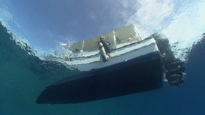 SCUBA Diver backward rolls into water shot from underwater