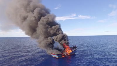 aerial drone shot of burning illegal fishing boat