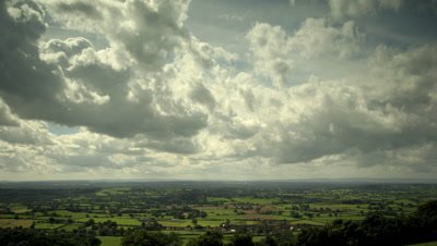 Slow pan right to left as clouds sweep towards camera over countryside. Taken from high viewpoint on Mendip Hills overlooking Somerset Levels, UK