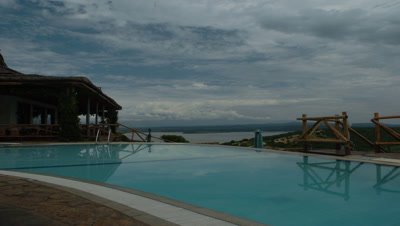 Medium wide angle Mweya African Safari Lodge swimming pool with grand view over vast savannah landscape and dramatic cloudscape in Queen Elizabeth National Park, Uganda