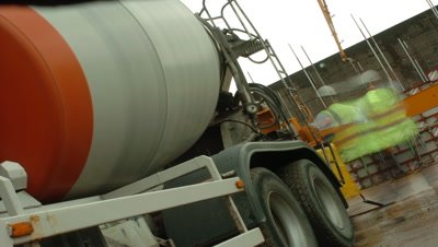 Mid shot cement mixer at building site, camera at 45 degree angle, lorry departs and returns, UK
