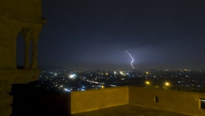 Wide angle overlooking Jaipur from hill top with temple building and featuring lightning over city