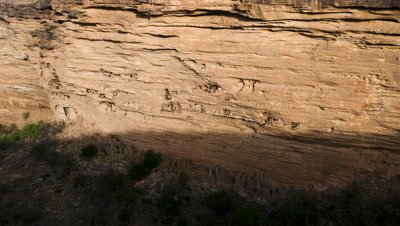 Big wide angle shadow moves down cliff escarpment and lights up Dogon cave houses in cliff face
