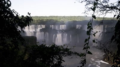 Medium wide angle dawn over large section of Iguazu Falls framed by forest