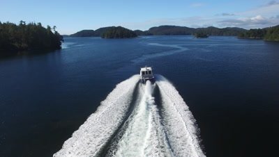 A speeding boat moving through the small isalnds in the Pacific Northwest region of Nimmo Bay in the Broughton Archipelago in Canada
