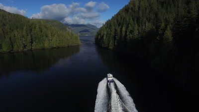 A speeding boat moving through the small isalnds in the Pacific Northwest region of Nimmo Bay in the Broughton Archipelago in Canada